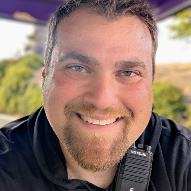 Smiling man with a radio device, representing the friendly service of Quick Change Tires, a mobile tire and battery care solution.